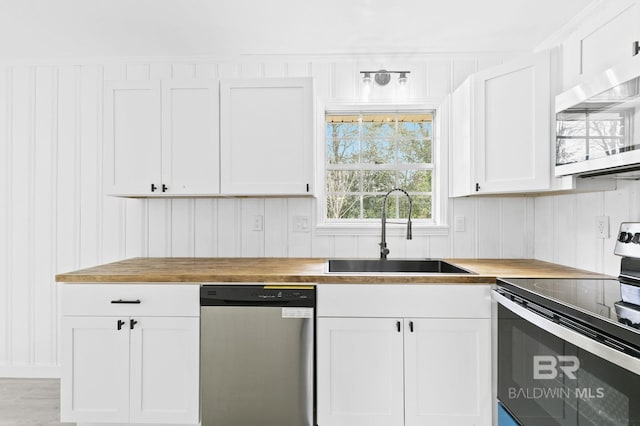 kitchen with sink, stainless steel appliances, wooden counters, and white cabinets