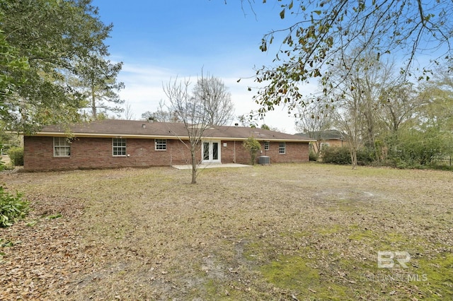 rear view of property with central AC and a yard