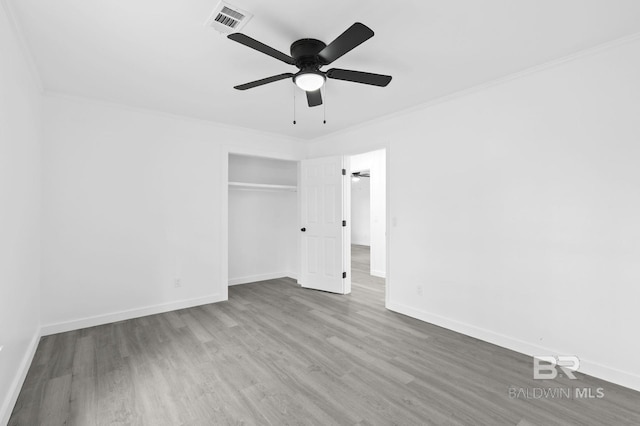 unfurnished bedroom with ceiling fan, a closet, crown molding, and hardwood / wood-style flooring