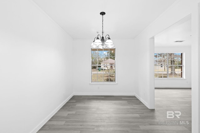 unfurnished dining area with hardwood / wood-style flooring, a notable chandelier, and ornamental molding