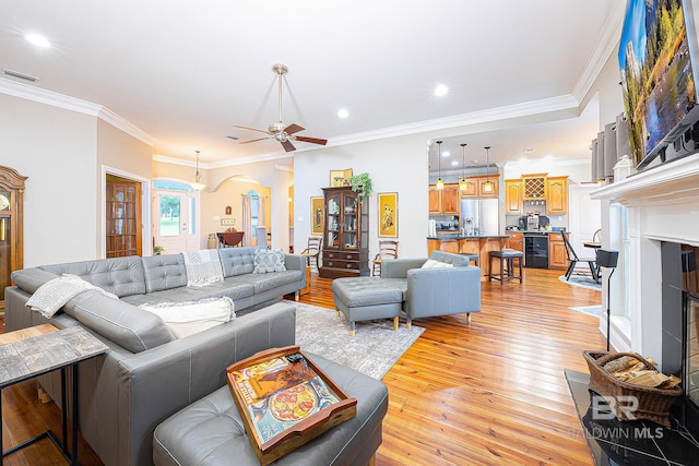 living room featuring light wood-type flooring, ornamental molding, wine cooler, and ceiling fan