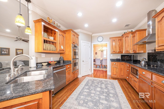 kitchen featuring light hardwood / wood-style flooring, decorative light fixtures, ceiling fan with notable chandelier, stainless steel appliances, and wall chimney exhaust hood