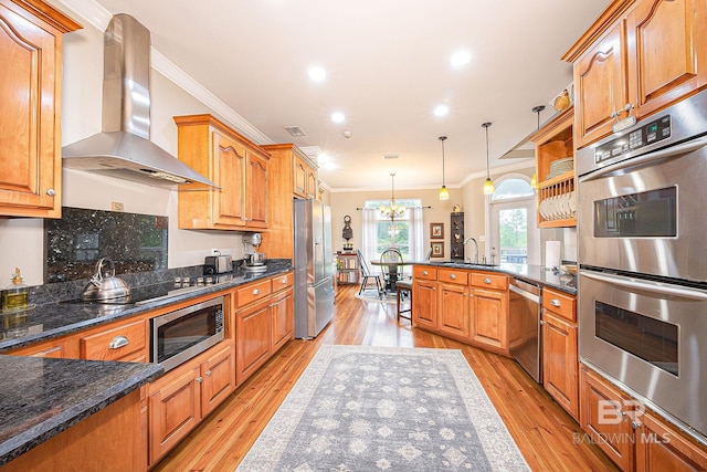 kitchen featuring light hardwood / wood-style floors, pendant lighting, stainless steel appliances, and wall chimney exhaust hood