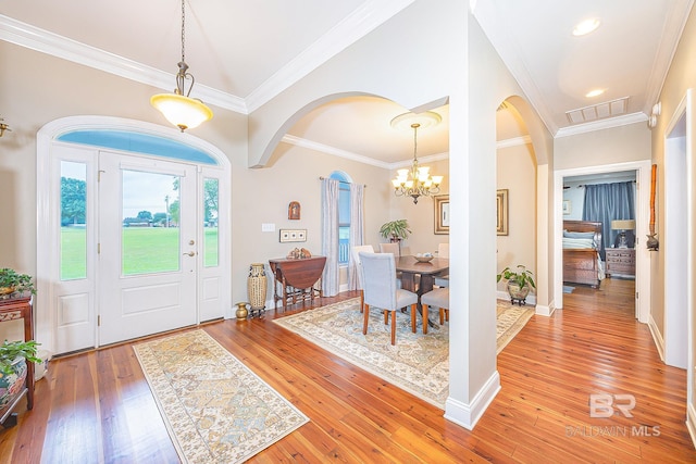 foyer entrance with ornamental molding, hardwood / wood-style flooring, and an inviting chandelier