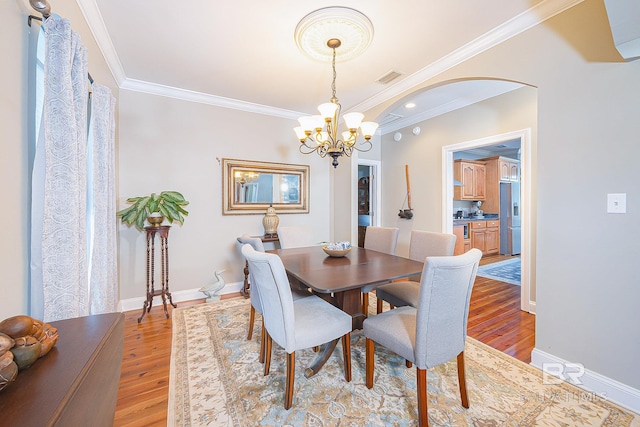 dining space featuring crown molding, light hardwood / wood-style flooring, and a chandelier