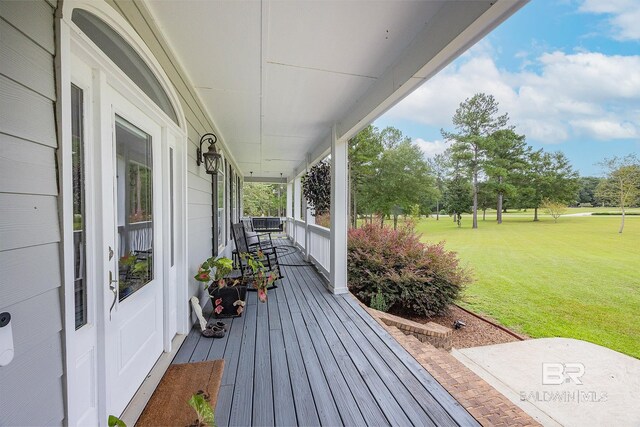 wooden terrace featuring a lawn and covered porch