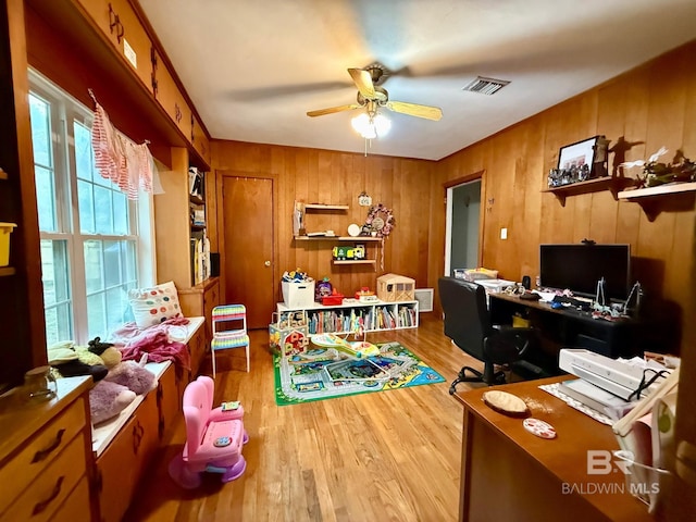 office space with wooden walls, ceiling fan, and light hardwood / wood-style flooring