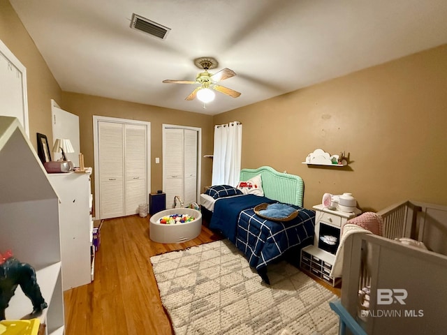 bedroom featuring multiple closets, ceiling fan, and hardwood / wood-style flooring