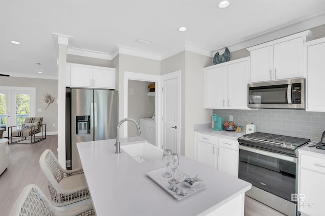 2831 Salt Dr, Orange Beach, AL 36561 - kitchen with stainless steel appliances, crown molding, washer / dryer, tasteful backsplash, and light wood finished floors
