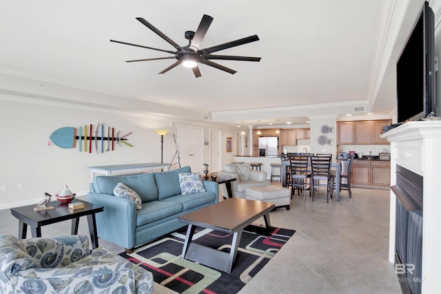 living room with ceiling fan, light tile patterned floors, ornamental molding, and a raised ceiling