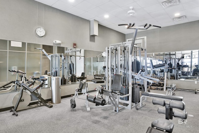 exercise room featuring a paneled ceiling and a towering ceiling