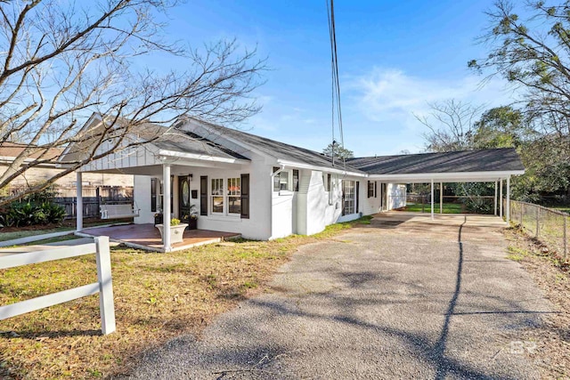 exterior space with an attached carport, stucco siding, fence, and aphalt driveway