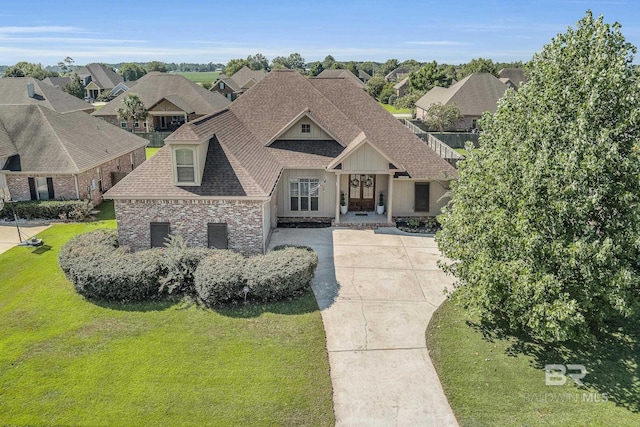 view of front of house featuring a residential view, roof with shingles, brick siding, and a front lawn