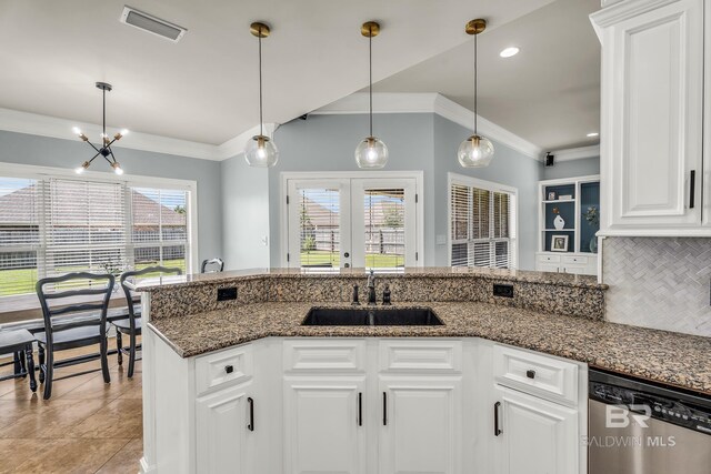 kitchen with dark stone counters, a sink, white cabinetry, dishwasher, and decorative light fixtures