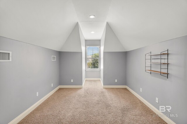 additional living space featuring vaulted ceiling, carpet floors, visible vents, and baseboards