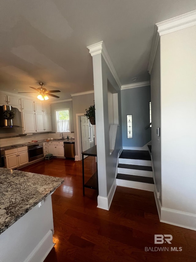 kitchen featuring dark wood-type flooring, backsplash, wall chimney range hood, stainless steel appliances, and ceiling fan