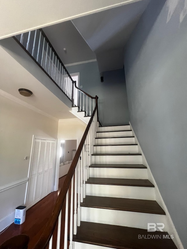 staircase featuring crown molding and a high ceiling