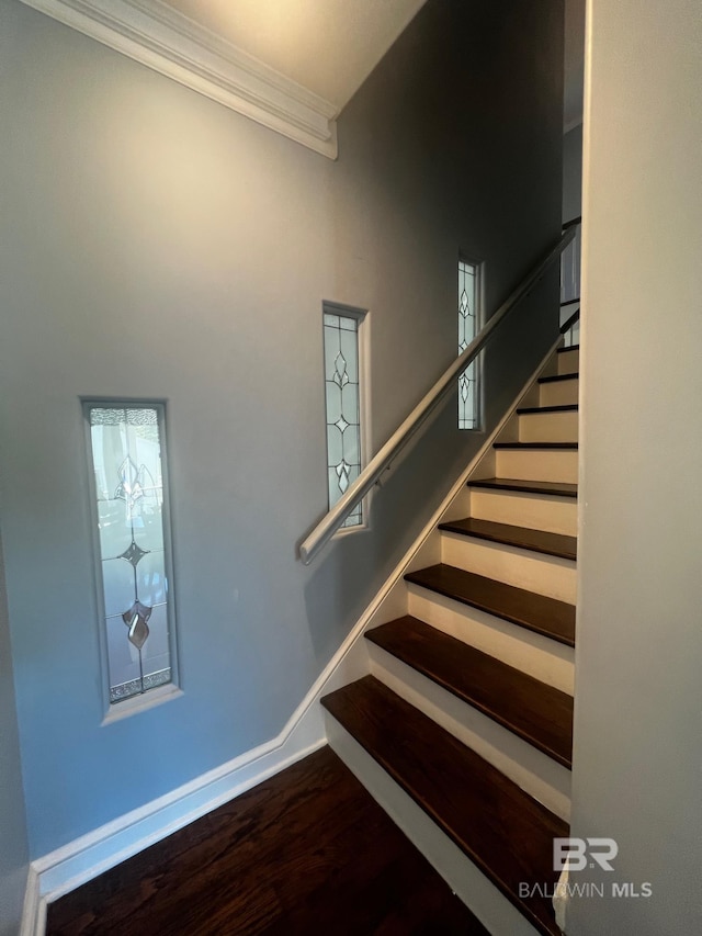 stairs with wood-type flooring and crown molding