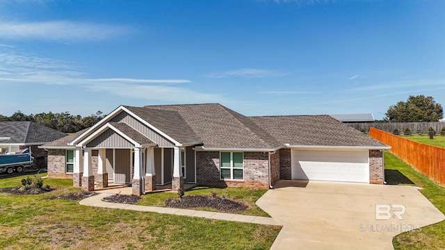 craftsman house with driveway, an attached garage, fence, a front yard, and brick siding