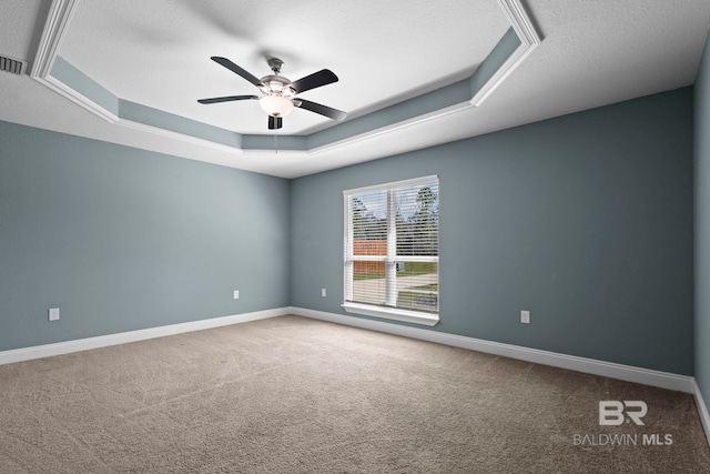 spare room featuring carpet, baseboards, a raised ceiling, and a ceiling fan