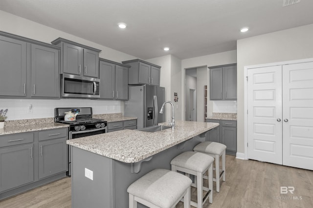 2345 Laurel St, Semmes, AL 36575 - kitchen featuring stainless steel appliances, light wood-type flooring, a kitchen bar, tasteful backsplash, and recessed lighting