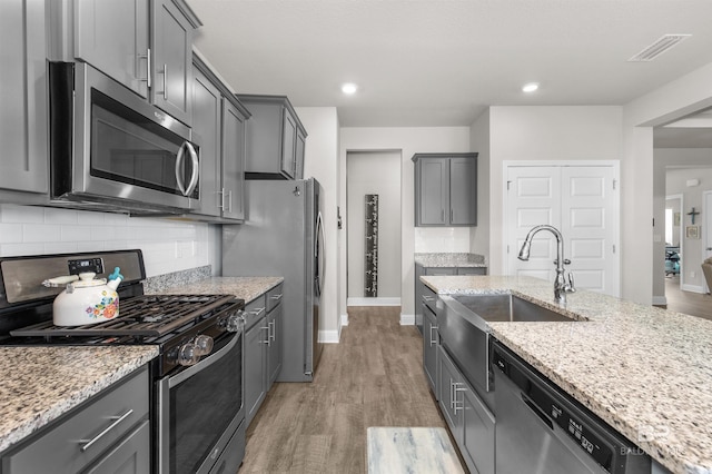 2345 Laurel St, Semmes, AL 36575 - kitchen with stainless steel appliances, light wood-style floors, light stone counters, tasteful backsplash, and recessed lighting