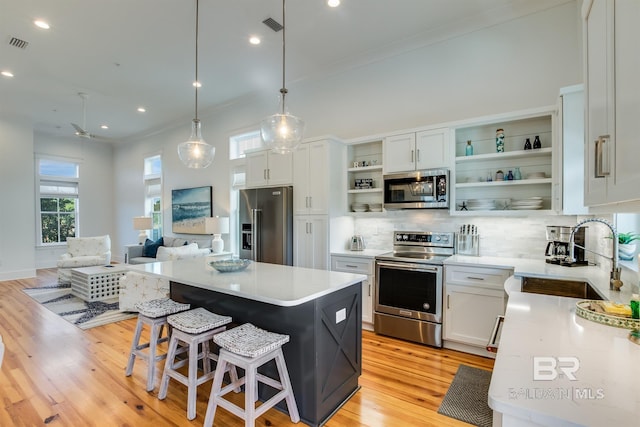 kitchen with white cabinets, appliances with stainless steel finishes, a kitchen island, and sink