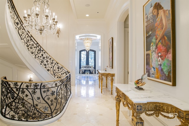 hallway with french doors, a high ceiling, a chandelier, and ornamental molding