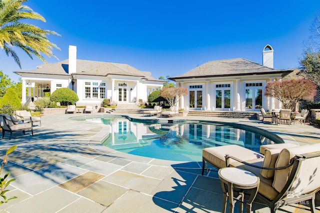 view of pool with a patio, french doors, and an outbuilding