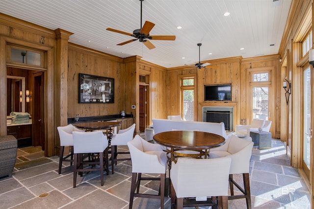 dining room with ceiling fan, wooden walls, crown molding, and wood ceiling