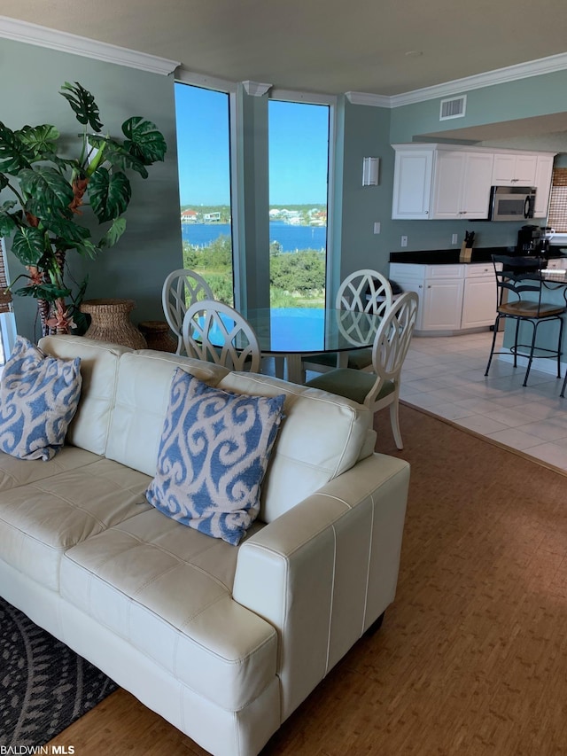 tiled living room featuring crown molding and a water view