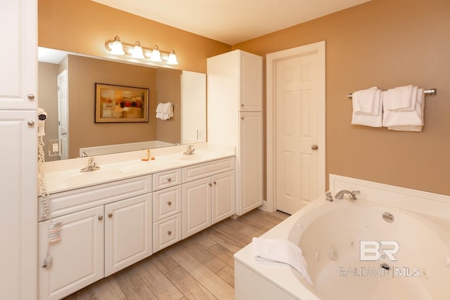 bathroom featuring wood finished floors, double vanity, a tub with jets, and a sink