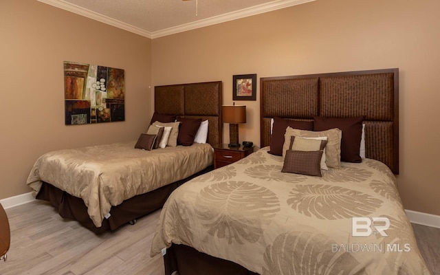 bedroom with crown molding, baseboards, and wood finished floors