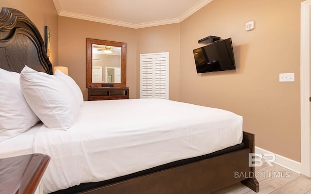 bedroom featuring baseboards, ornamental molding, and wood finished floors