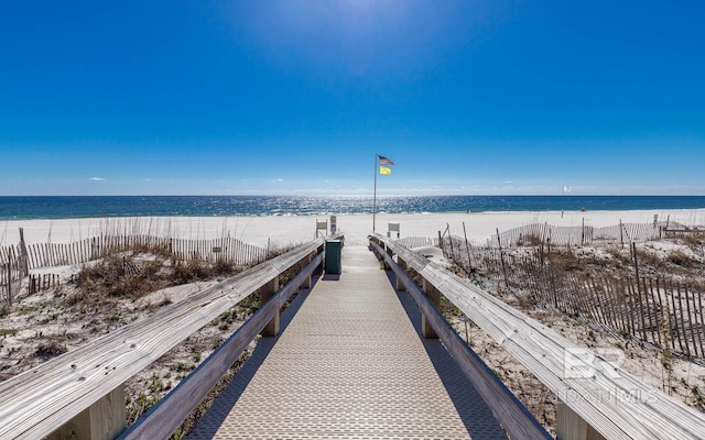 surrounding community with a beach view, fence, and a water view