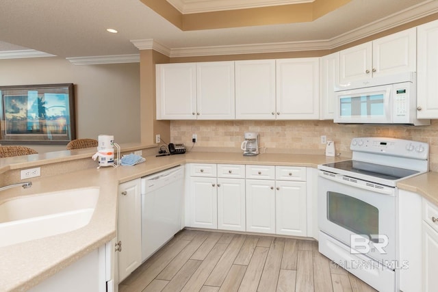 kitchen with white appliances, a sink, light wood-style floors, backsplash, and crown molding