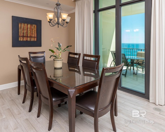 dining area featuring light wood-type flooring, baseboards, ornamental molding, and a chandelier