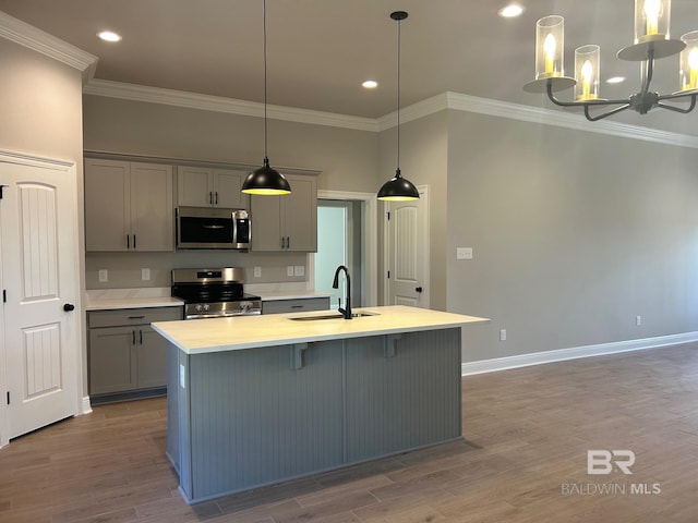 kitchen featuring stainless steel appliances, hanging light fixtures, gray cabinetry, and an island with sink