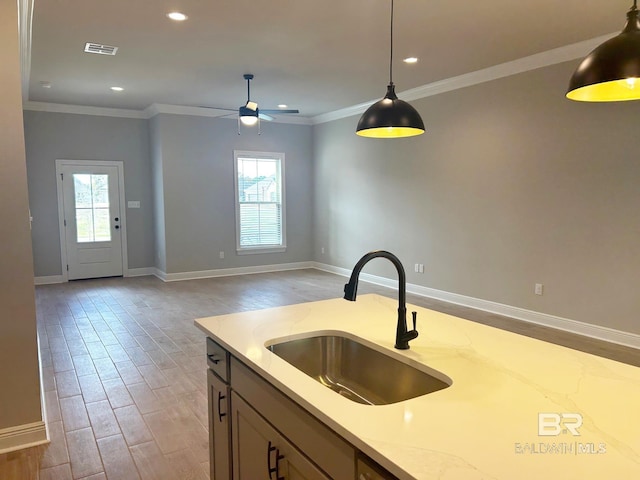 kitchen with light stone countertops, sink, pendant lighting, light hardwood / wood-style floors, and ornamental molding