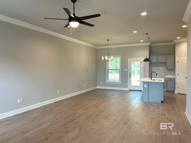 kitchen with ornamental molding, a center island with sink, pendant lighting, and wood-type flooring