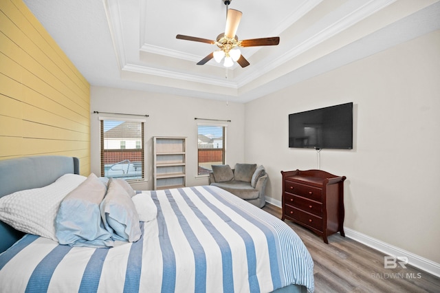 bedroom featuring crown molding, a tray ceiling, wood-type flooring, and ceiling fan