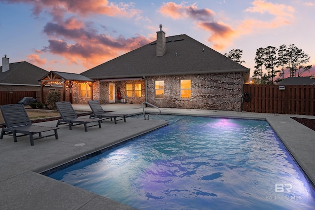 pool at dusk featuring a patio