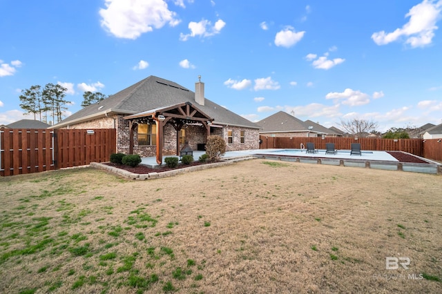 rear view of property featuring a fenced in pool and a patio