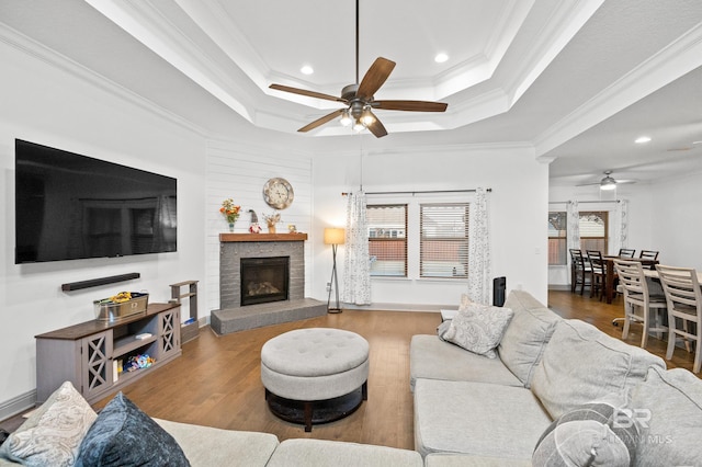 living room with crown molding, a tray ceiling, and hardwood / wood-style flooring