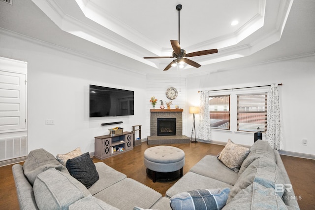 living room featuring hardwood / wood-style flooring, ceiling fan, ornamental molding, and a tray ceiling