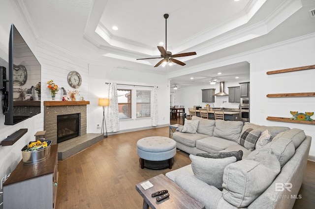 living room featuring hardwood / wood-style flooring, ornamental molding, and a tray ceiling