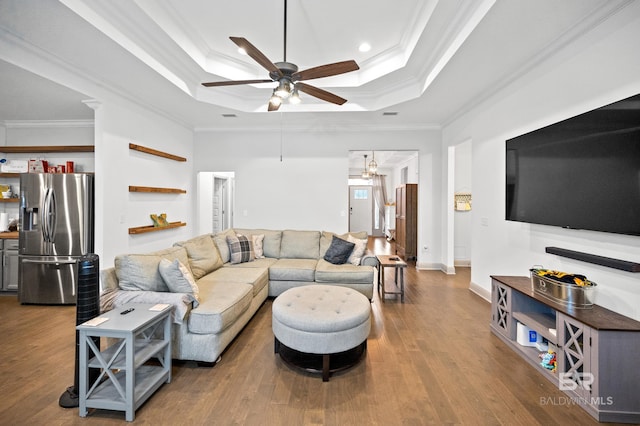 living room featuring hardwood / wood-style flooring, ceiling fan, ornamental molding, and a tray ceiling