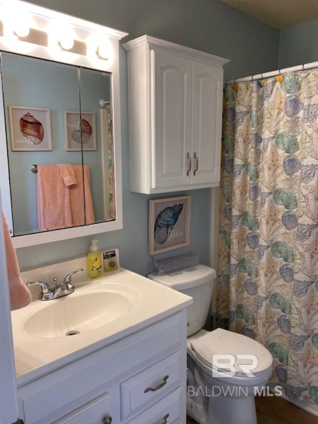 bathroom featuring vanity, curtained shower, and toilet