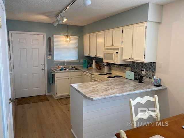 kitchen featuring rail lighting, backsplash, white cabinets, kitchen peninsula, and white appliances