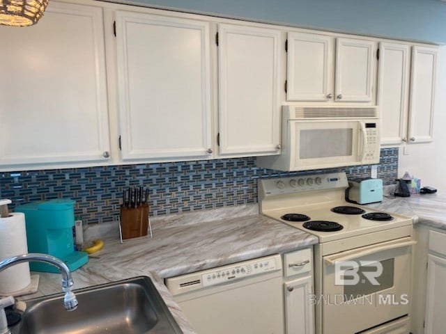 kitchen with sink, white appliances, tasteful backsplash, light stone countertops, and white cabinets